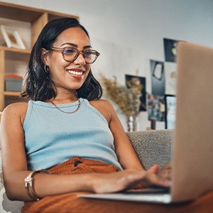 Woman smiling while working on laptop at home