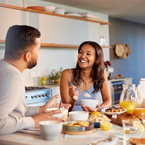 Couple smiling at each other while eating in kitchen
