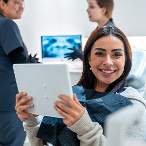 Patient smiling while holding mirror in treatment chair