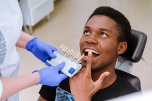 Young man in dentist's chair looking at veneers.