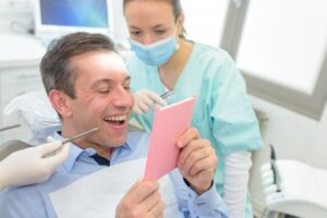 Man looking at his perfect teeth after a cosmetic dental treatment